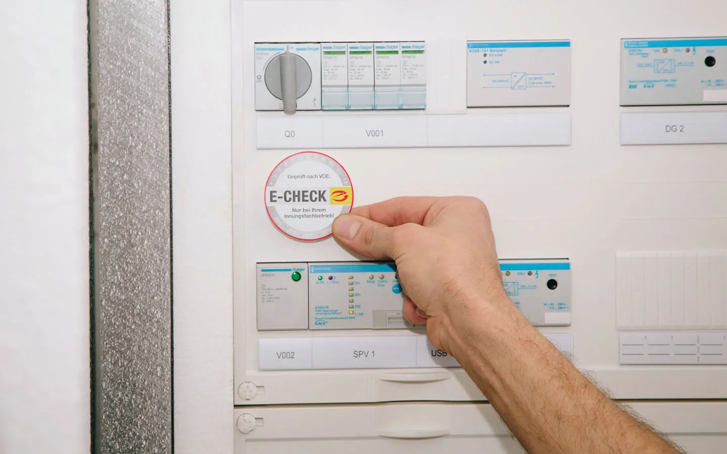 E-CHECK - Mitarbeiter klebt in der Verteilung die E-CHECK Plakette an &middot; Thoma-Laudan Gebäudetechnik