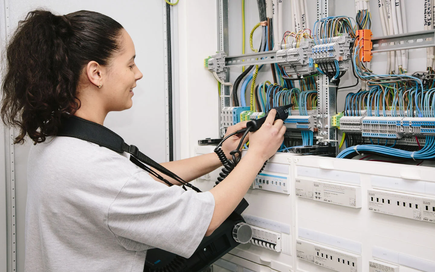E-CHECK - Mitarbeiterin prüft im Schaltschrank mit einem Meßgerät &middot; Thoma-Laudan Gebäudetechnik